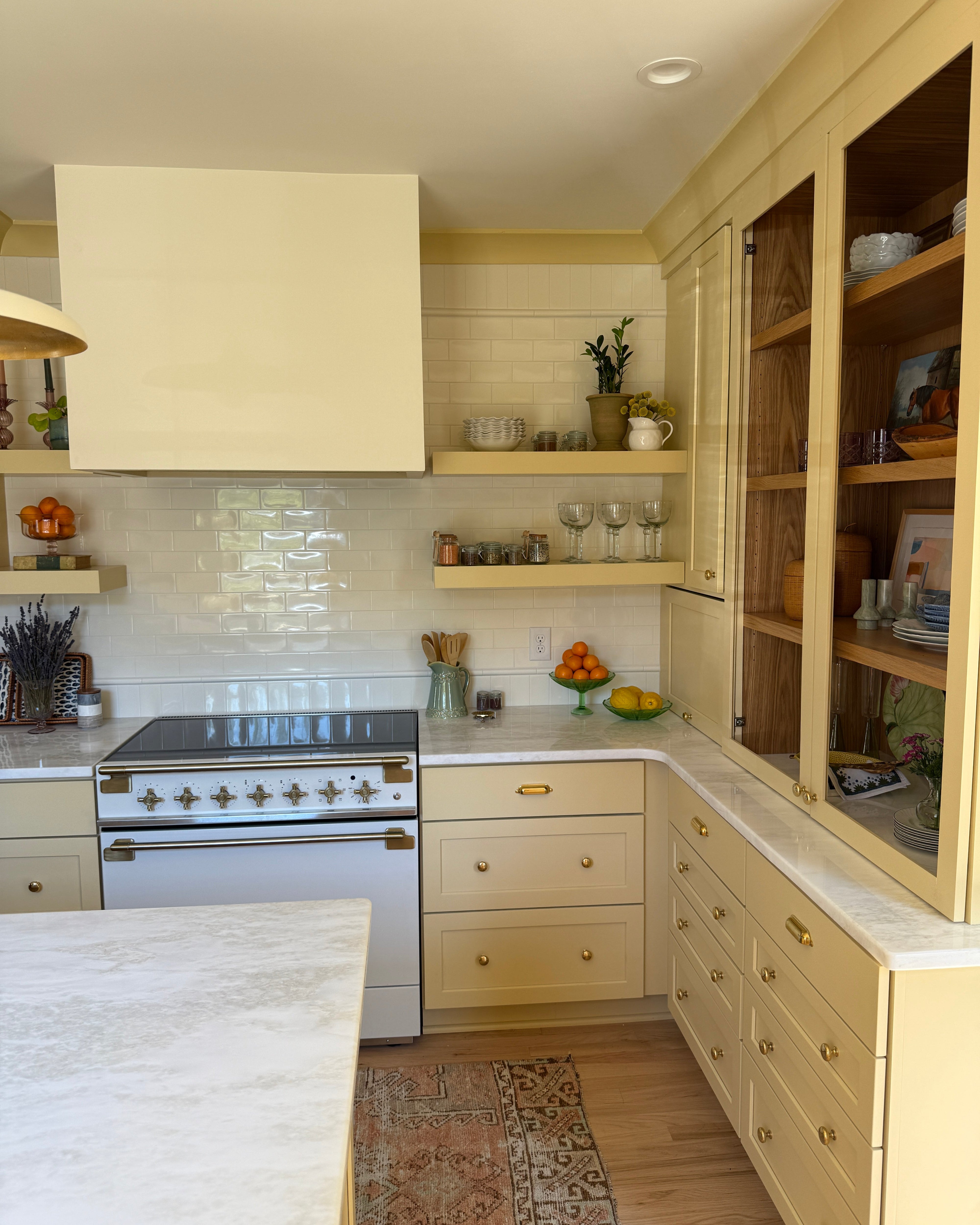 Modern yellow kitchen with white cabinets, tiled walls, and a stove.