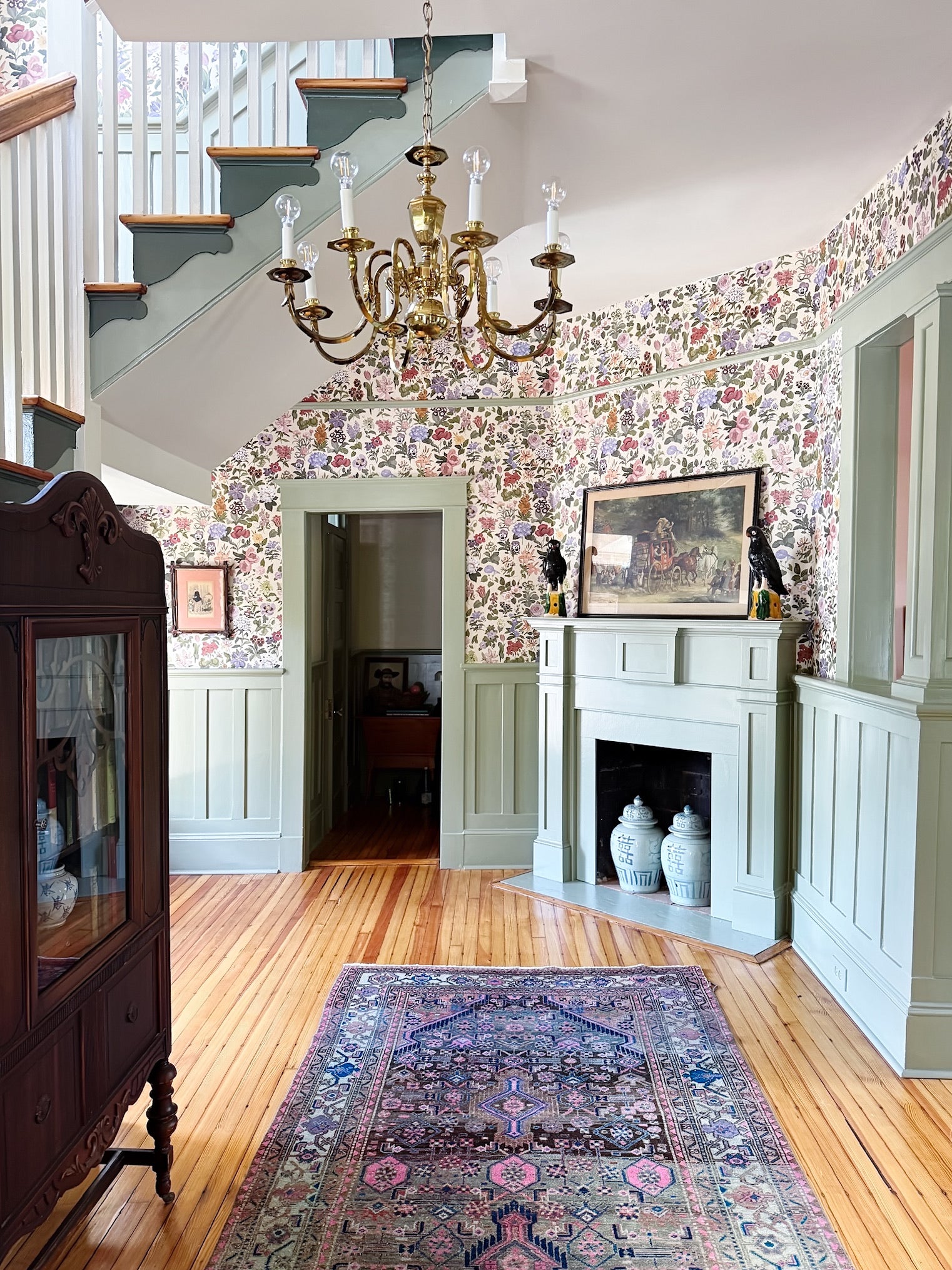 ENtryway with floral wallpaper, chandelier, and fireplace.
