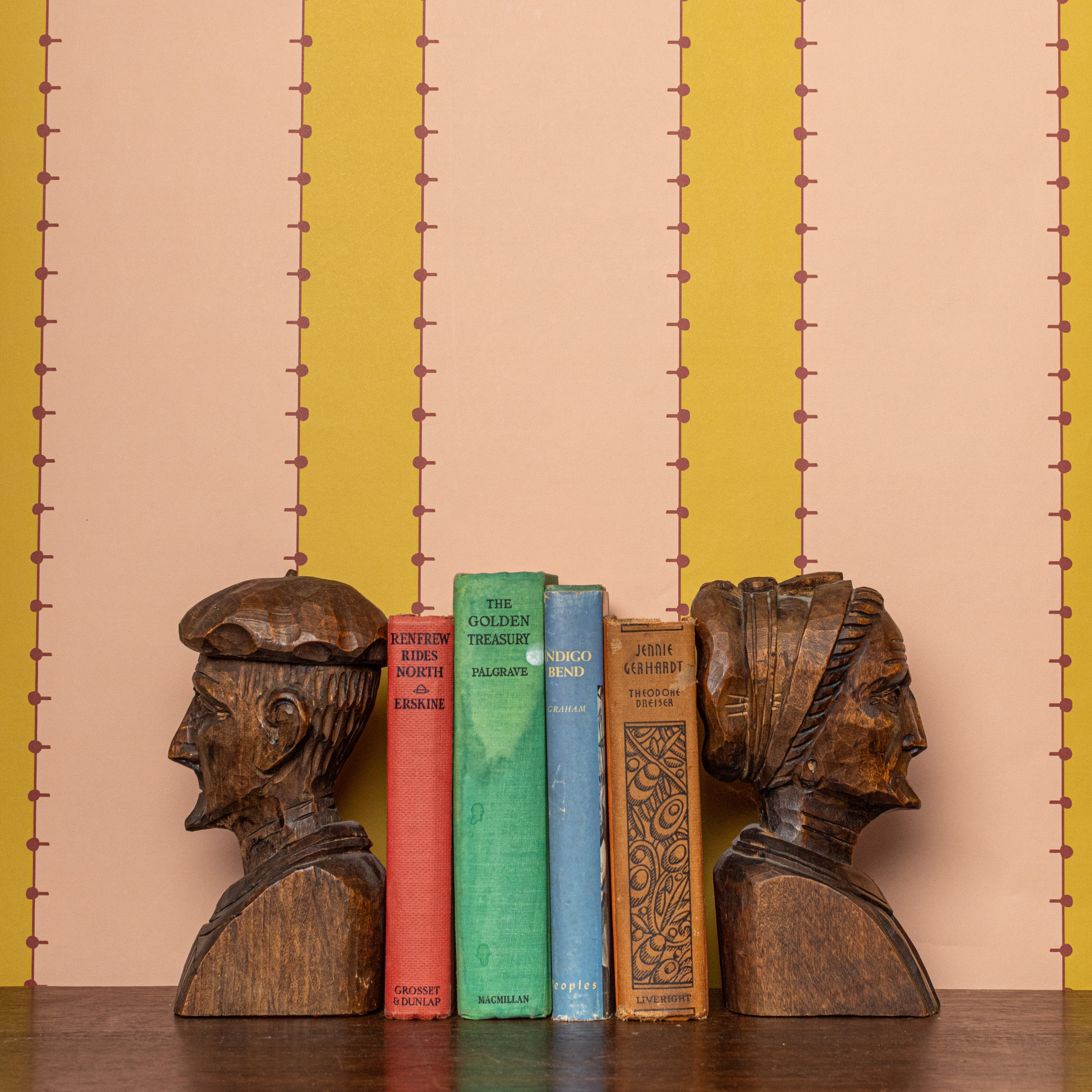 Wooden bust bookends with colorful striped wallpaper in peach and chartreuse
