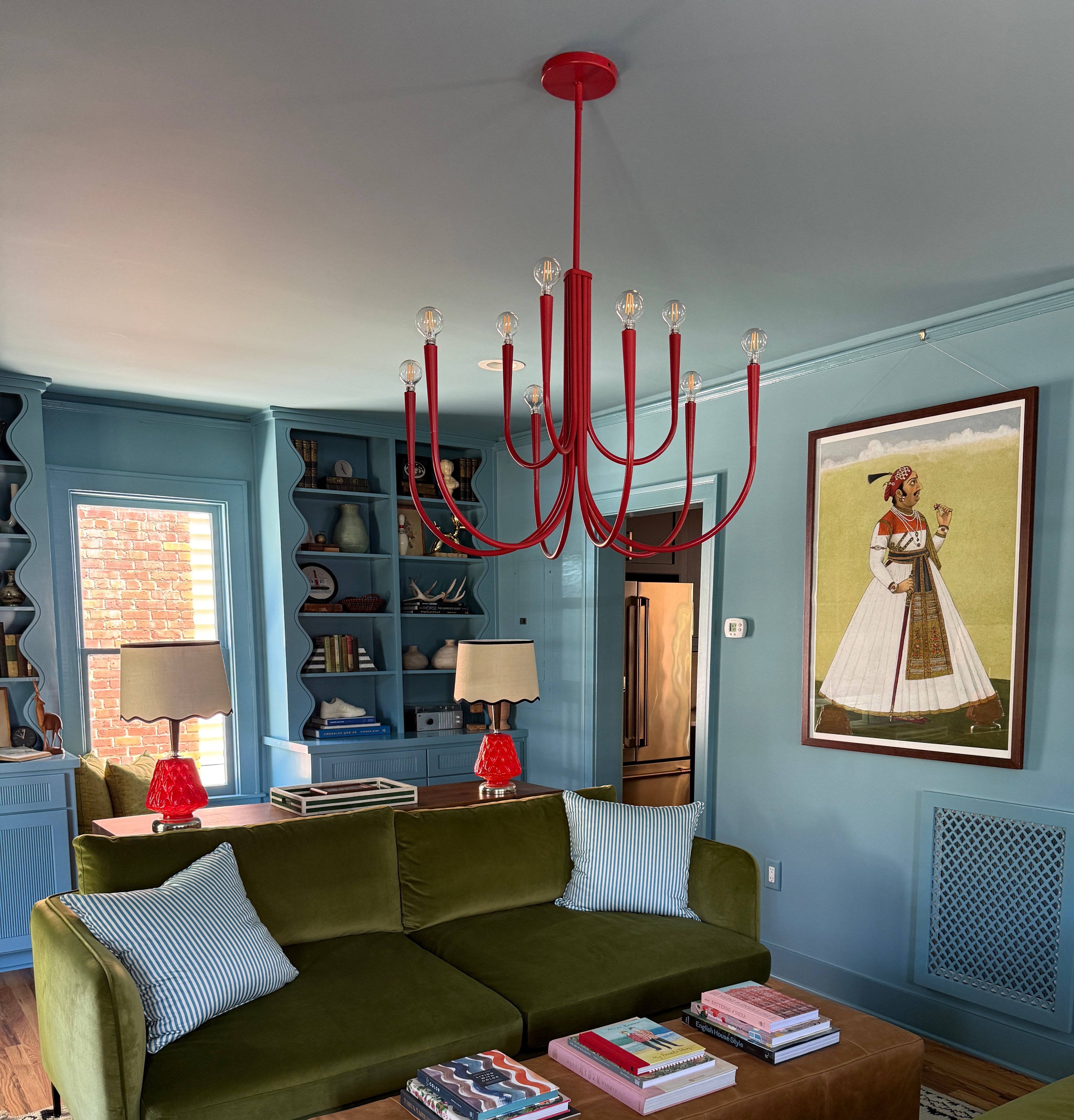 Blue living room with green couches and red chandelier