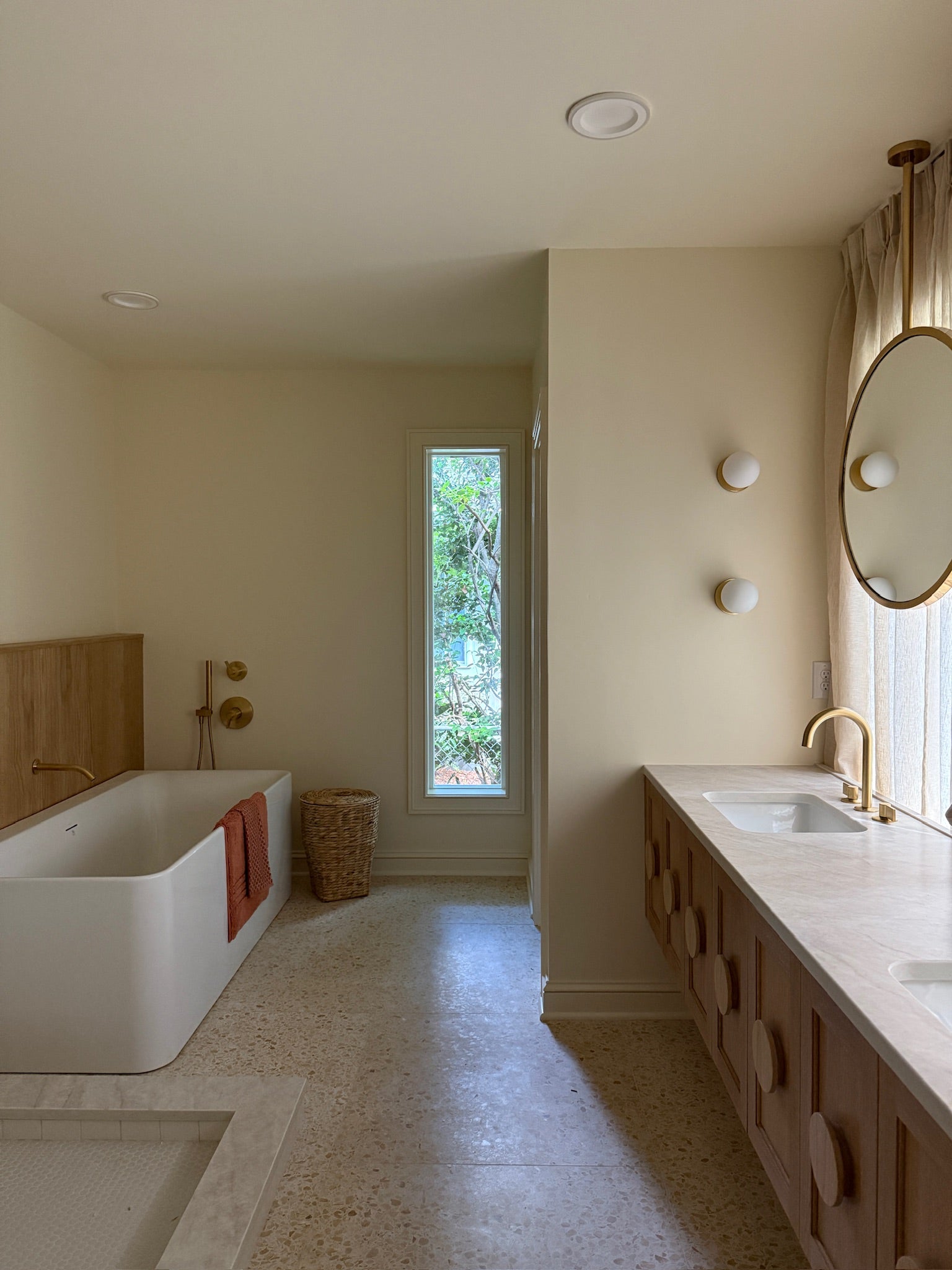 Modern bathroom with a bathtub, sink, and large mirror.