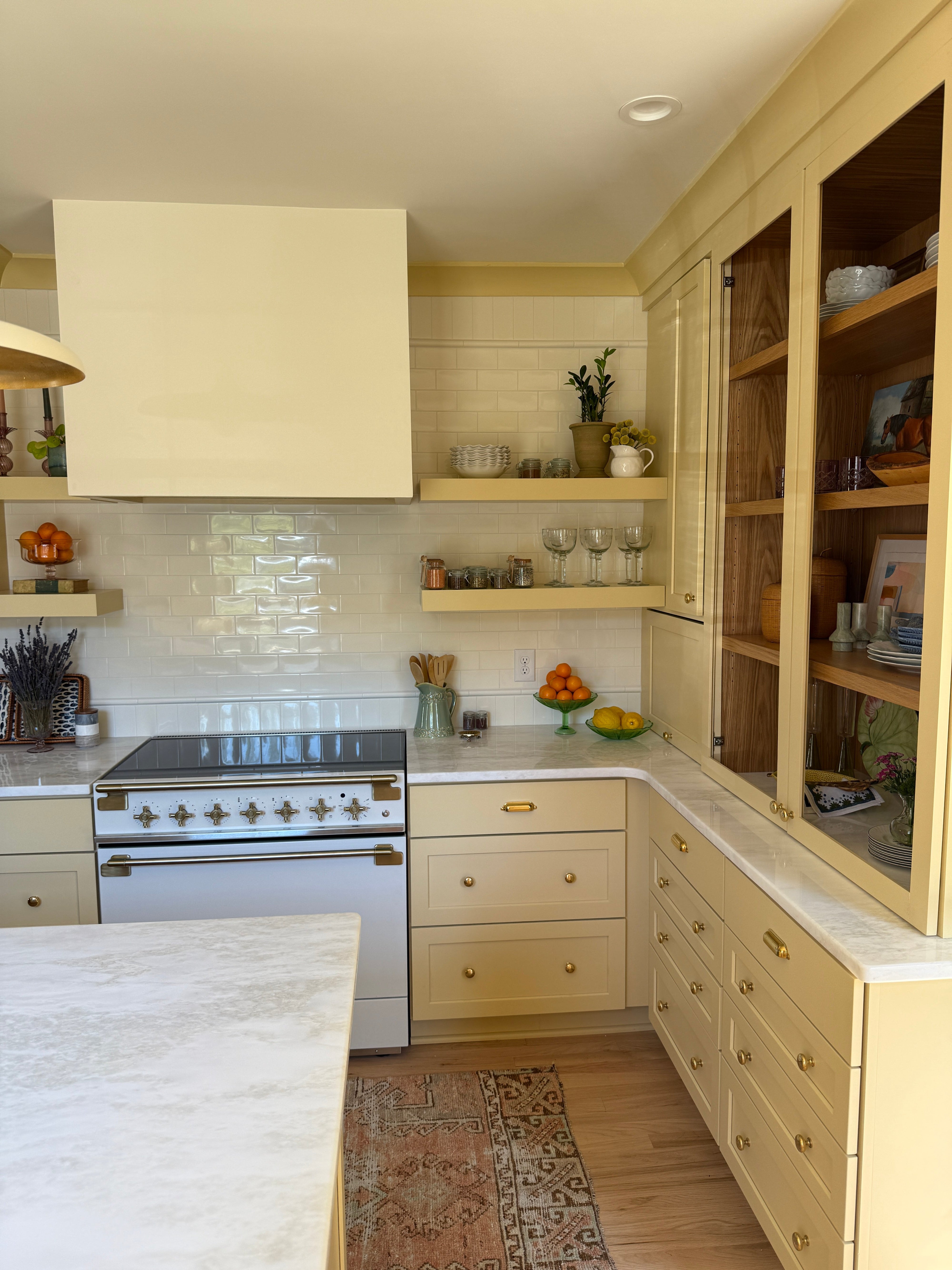 Modern yellow kitchen with white cabinets, tiled walls, and a stove.