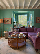 Living room with Purple couch, teal walls, rattan coffee table