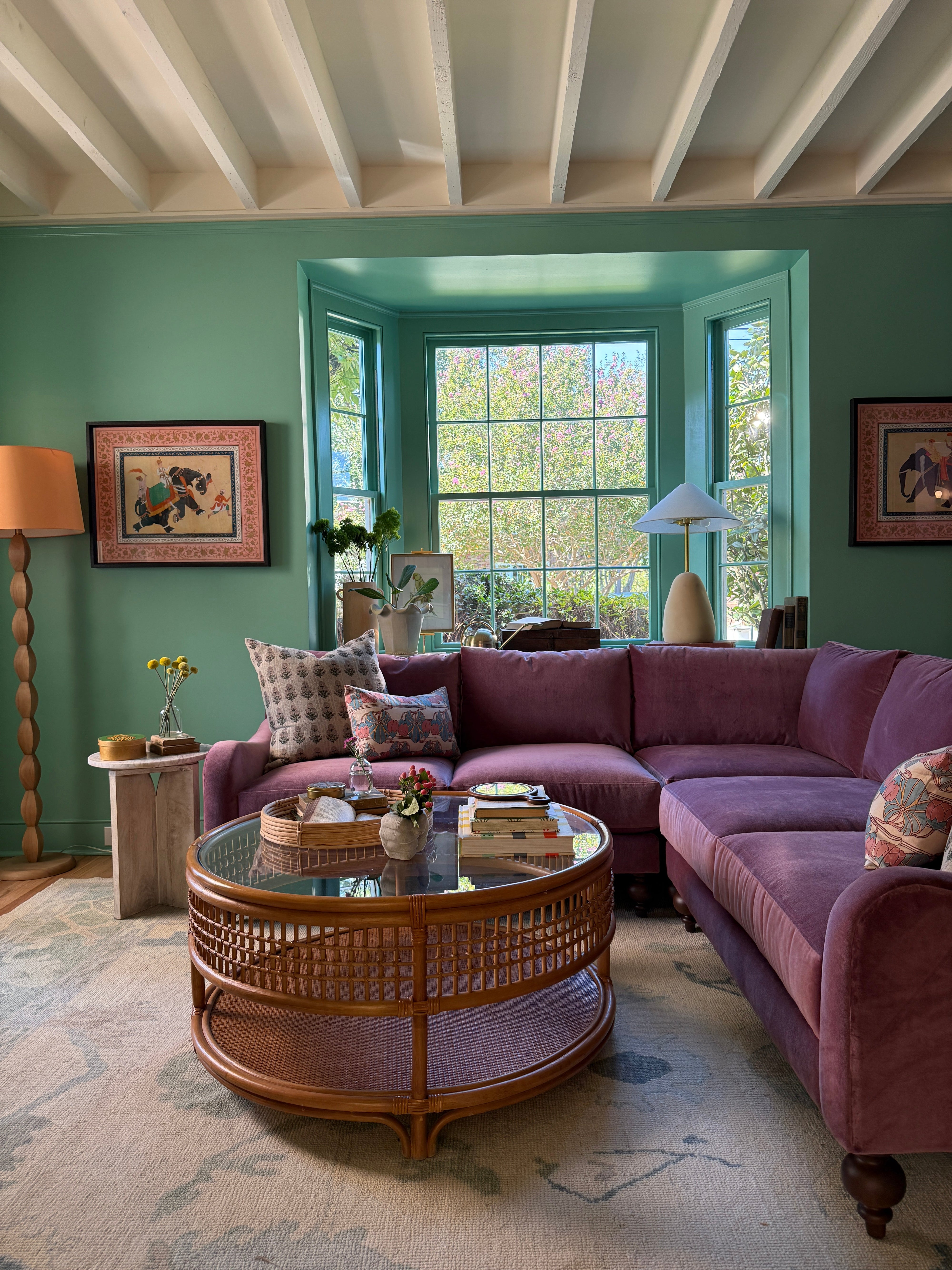 Living room with Purple couch, teal walls, rattan coffee table