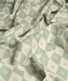 Fabric with a pattern of green and pink diamonds with flowers in middle