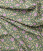 Floral patterned fabric with lavender flowers and green leaves on a green background