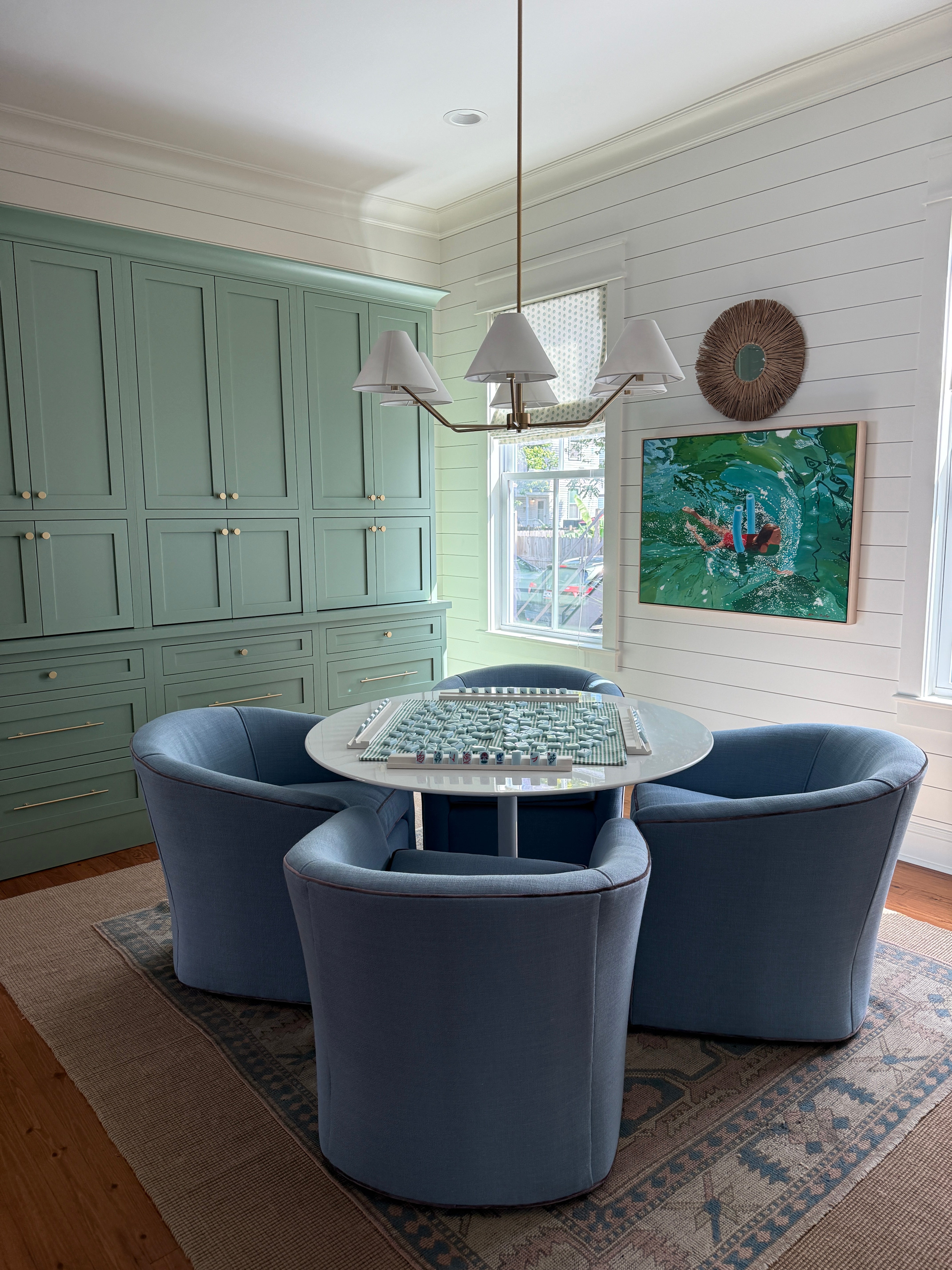 Game area with green built in cabinets, blue chairs and white shiplap walls