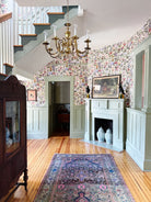 ENtryway with floral wallpaper, chandelier, and fireplace.