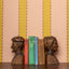 Wooden bust bookends with colorful striped wallpaper in peach and chartreuse