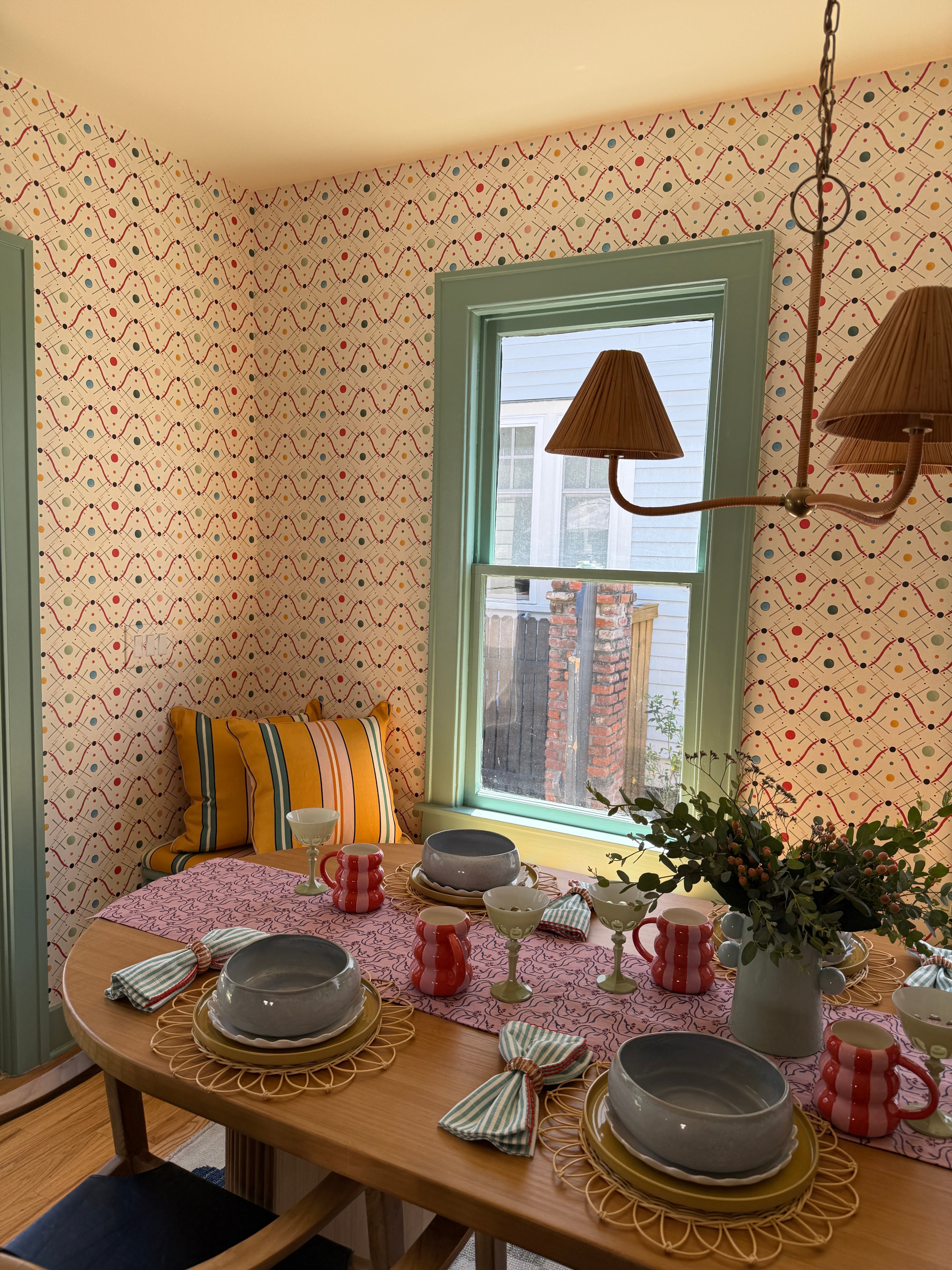 Fun and airy, breakfast room with green trim and funky wallpaper