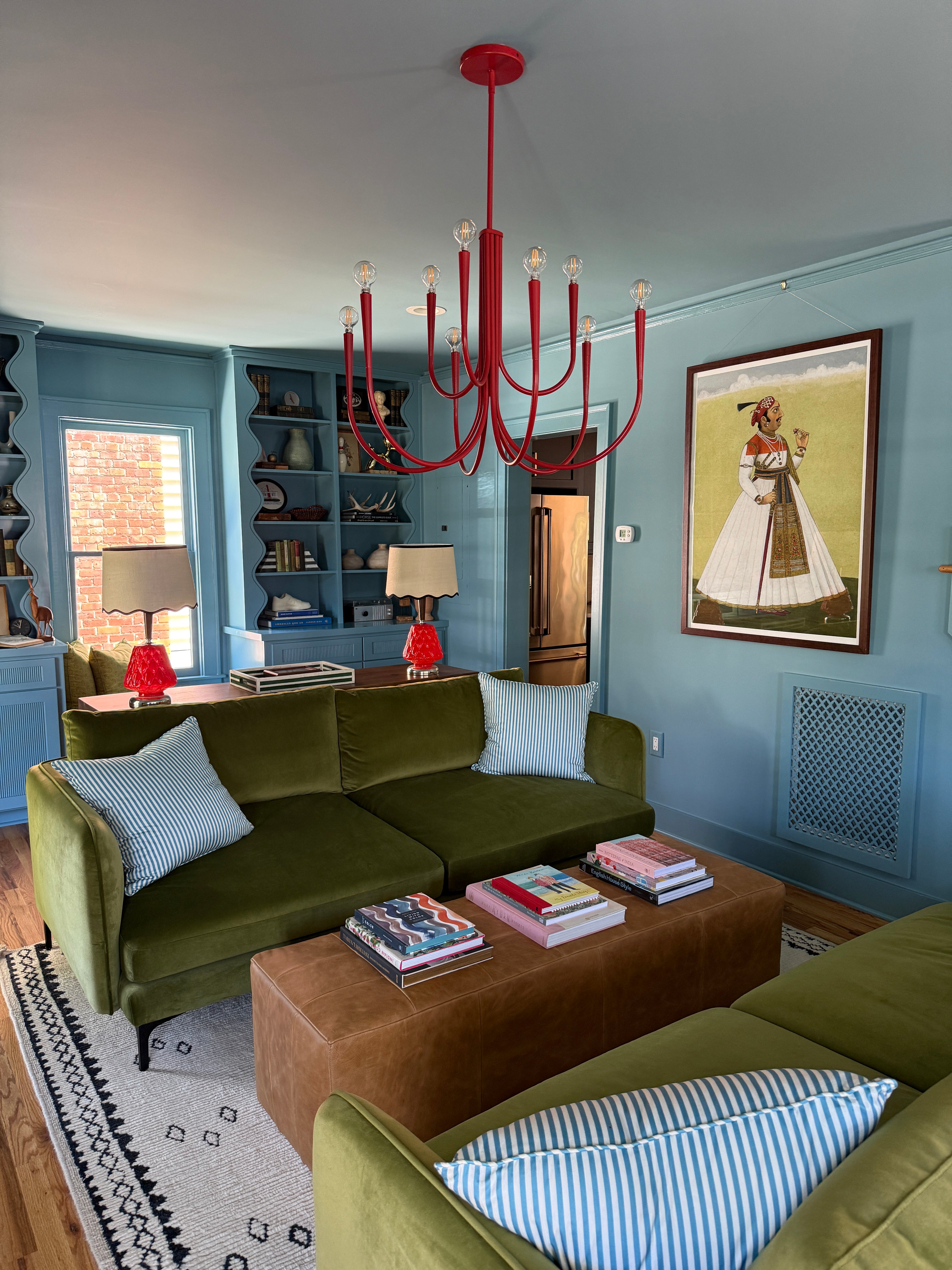 Blue living room with green couches and red chandelier