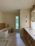Modern bathroom with a bathtub, sink, and large mirror.