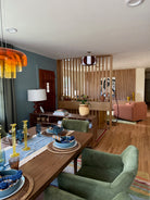 Modern living room with a dining table set, green armchair, and decorative elements.