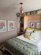 Murphy Bed with floral bedspread, colorful pillows, and bookshelf.