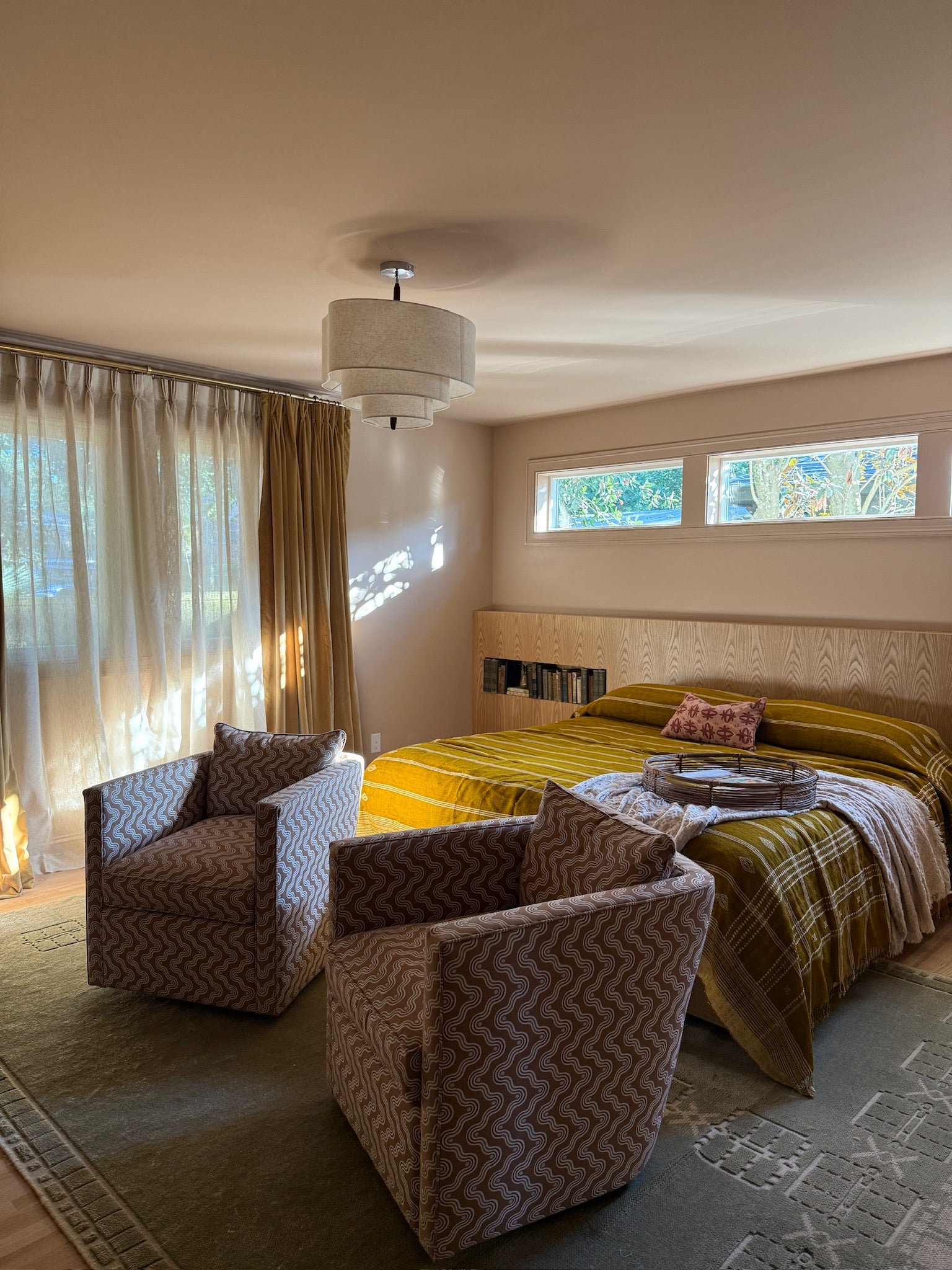 Modern bedroom with a bed, armchair, and large windows.